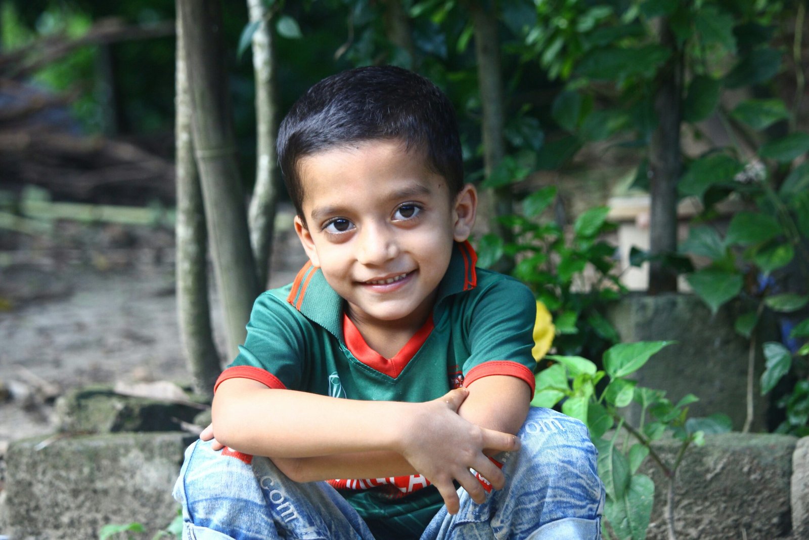 a young boy sitting on a rock